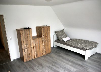 Eines der Schlafzimmer der jungen Menschen, die in der DBT-A Wohngruppe leben. Es steht ein Bett in der Ecke des Raums sowie ein Schrank.